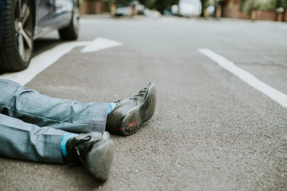 Person in suit lying on asphalt street.